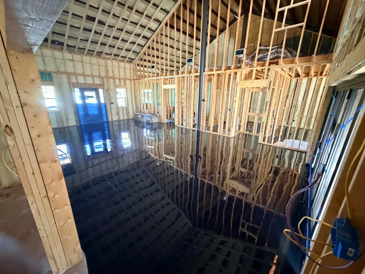 Reflective black epoxy floor installed across a newly framed interior