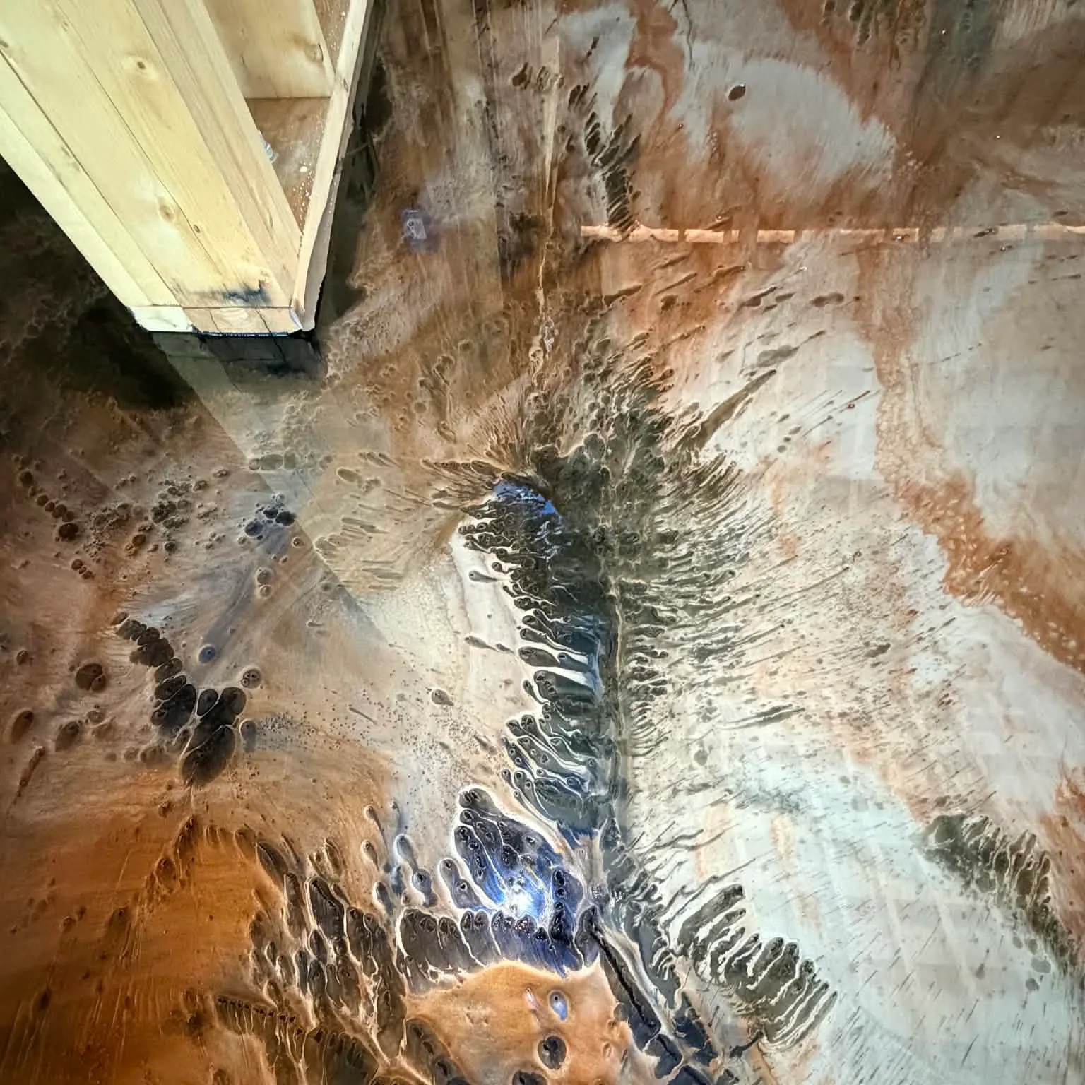 Copper, pearl, black, and cobalt metallic epoxy flowing around a framed interior wall