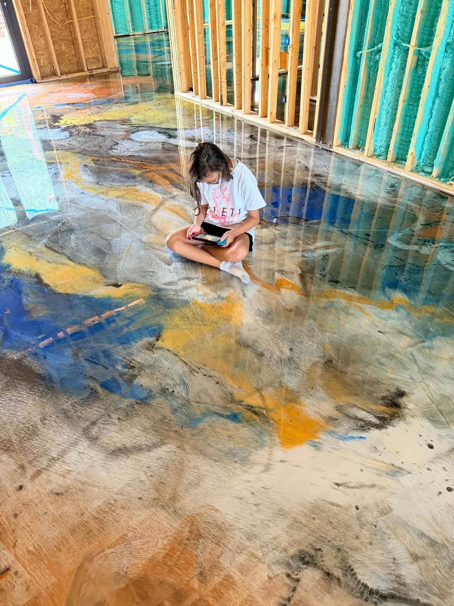 Installer seated beside a completed reflective metallic epoxy floor