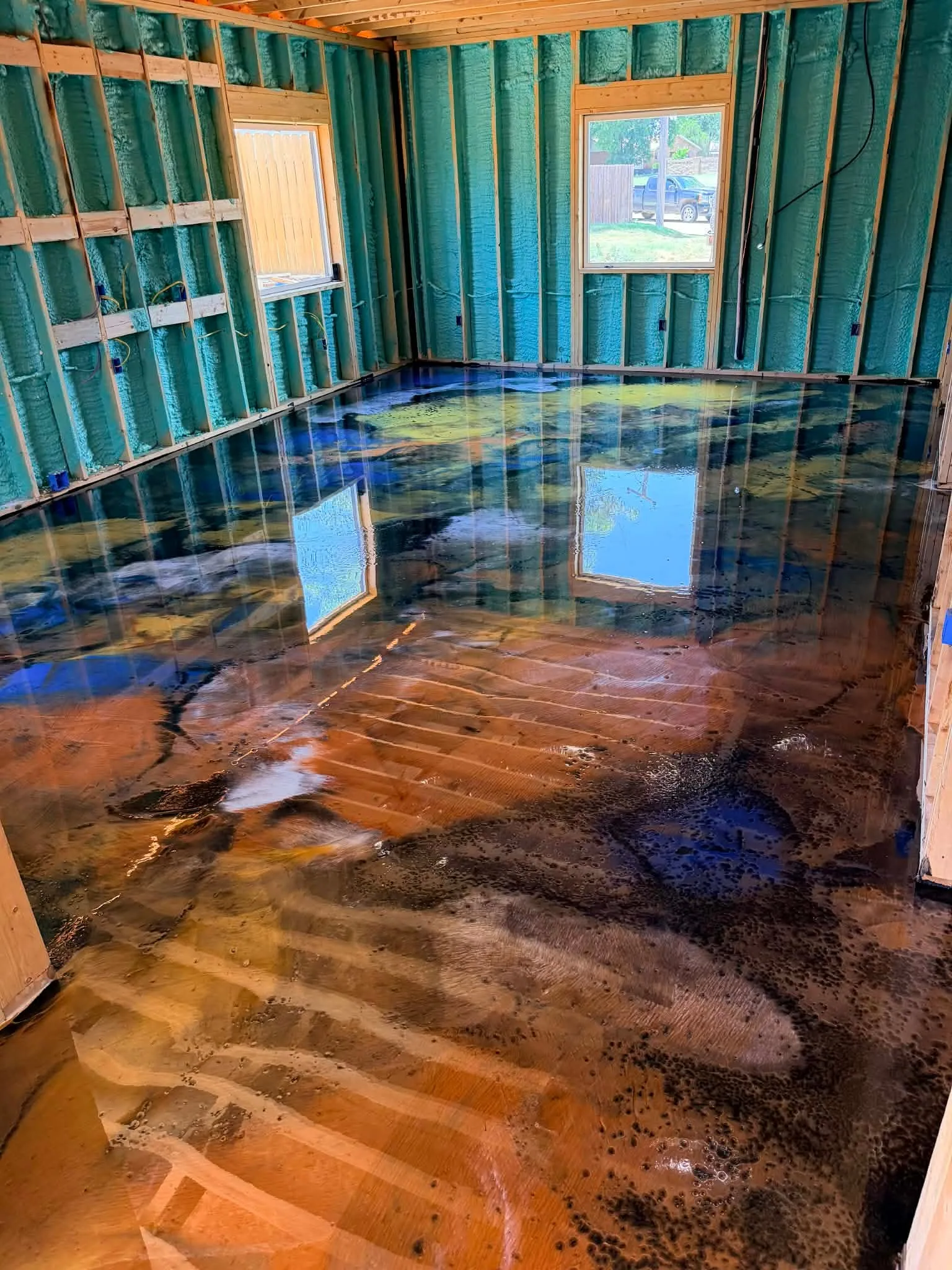 Finished blue, gold, copper, and black metallic epoxy floor in a newly framed room
